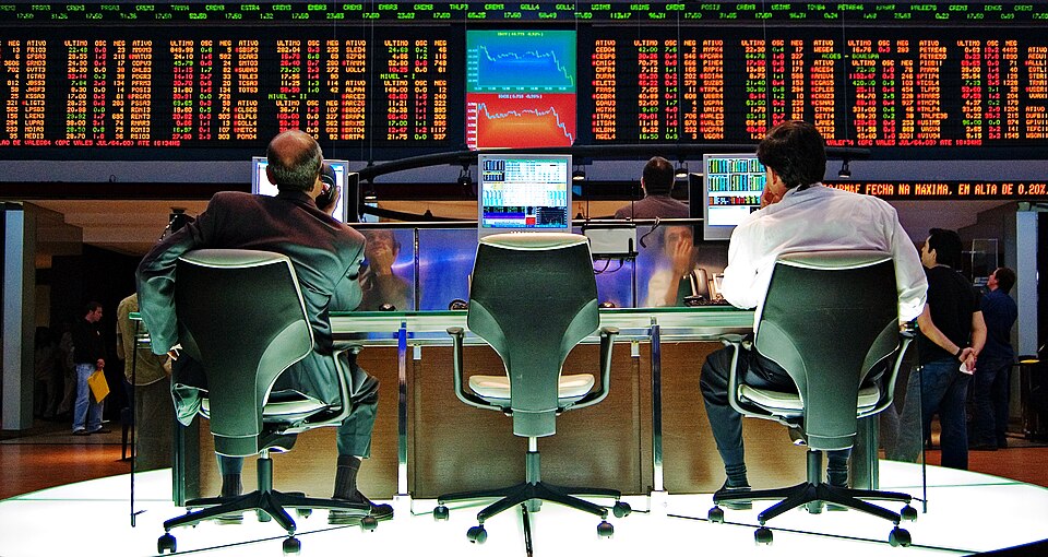A Bolsa de Valores de São Paulo, hoje integrada à B3. Movimentos do Ibovespa refletem expectativas de investidores sobre lucros, juros, risco e políticas econômicas — mas não funcionam como medida direta de bem-estar social. Crédito: Rafael Matsunaga, via Wikimedia Commons — CC BY 2.0.